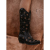 Black cowboy boot with star patterns on a horse's leg