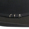Close-up of a black hat with decorative metal bands on a dark background