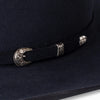 Close-up of a black hat with decorative silver buckle and strap on a dark background