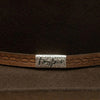 Close-up of a brown leather belt with a silver buckle on a dark background