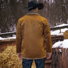 Person wearing a brown leather jacket and cowboy hat standing in a snowy landscape with hay and wooden structures.