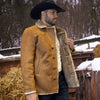 Man wearing a brown leather coat with fur lining outdoors in a snowy landscape.