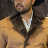 Man wearing a brown coat with fur collar in a forest setting