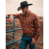 Man in cowboy attire with a patterned shirt and black hat leaning against a blue metal gate.