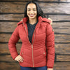 Woman wearing a red puffer jacket against a wooden wall