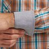 Close-up of a plaid shirt with rolled-up sleeve and hand adjusting it.